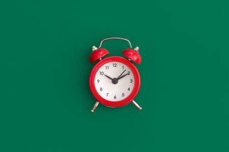 Red alarm clock on green background