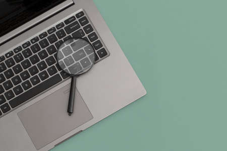Magnifier on laptop on green background. Business concept, strategyの写真素材