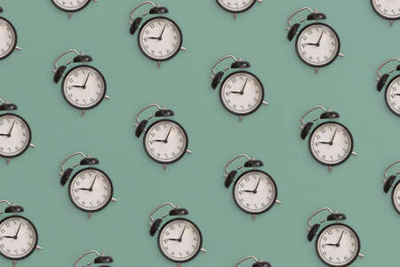 Pattern composition of black antique alarm clock on green background. Flat lay composition. Top view.の写真素材