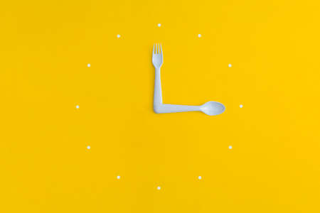 Cutlery watch dial on yellow background.