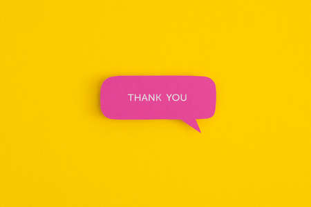 Paper speech bubbles with the word Thank you on a yellow background. Top view with copy space. Flat...