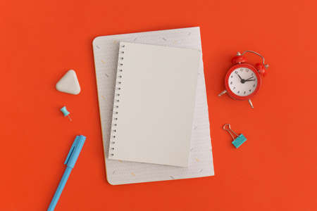 Red alarm clock and notebooks with space for text on red background