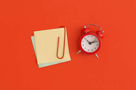 Red alarm clock and sticky notes with space for text on red backgroundの写真素材