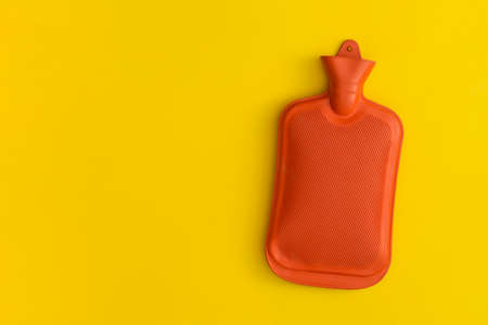 Hot water bottle on a yellow background. Top view with copy space. Flat lay.の写真素材