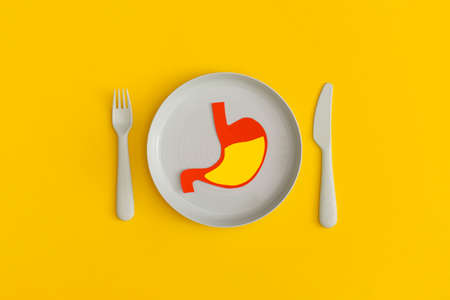 Blue plate with fork and spoon on a yellow background. Top view. Flat lay.の写真素材