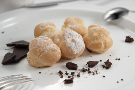 Profiteroles with chocolate on a white plateの写真素材