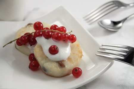 Curd fritter with cream and berries on a white plateの写真素材