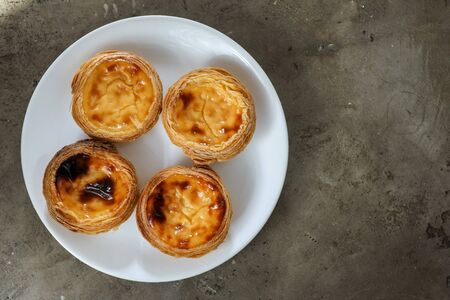 Portuguese pasteis of cake with custard on white plate on textured background.の写真素材