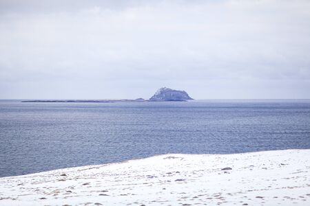 The shoreline of the ocean and beautiful snow-capped mountains on the horizon. The landscape of icelandの写真素材
