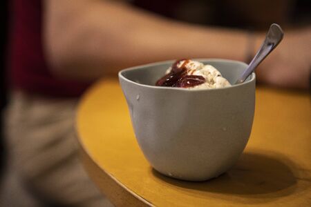 ramekin with soft ice cream, jam and spoon in a glass
