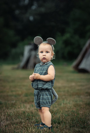 Cute little girl in a dress with a mouse ears in the forestの写真素材