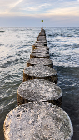 Wooden breakwater on the sea shore in the evening time.