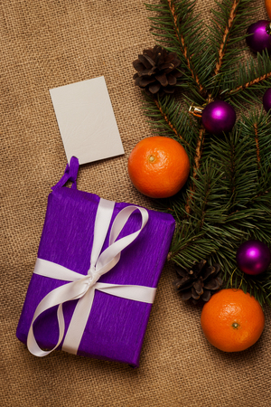 Purple gift with postcard, orange tangerines, fir-cones, Christmas decorations and fur-tree branchの写真素材