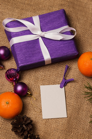 Purple gift with postcard, orange tangerines, fir-cones, Christmas decorations and fur-tree branchの写真素材