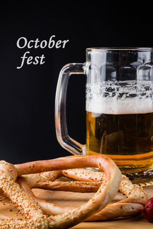 A fresh glass of cold light beer and pretzel on the wooden cutting board with text, background of the Oktoberfest.の写真素材