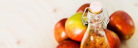 Bottle of fresh apple juice and near autumn apples. Wooden background, space for text, view from above.の写真素材