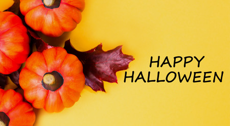 Halloween holiday background. Halloween pumpkin jack o lantern decor on yellow background. Text happy halloween. View from above.の写真素材