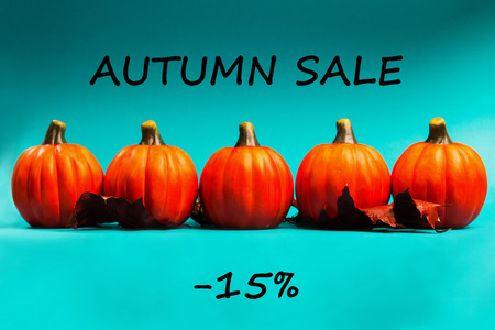 Autumn sale background. Orange pumpkins with red dried oak leaves on blue background. Text autumn sale -15%.の写真素材