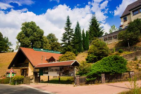 Rathen, Germany - August 4th, 2018: Rathen, Saxon Switzerland National Park. View of german houses on blue sky background with clouds. Road leading to Bastei Bridge.のeditorial素材