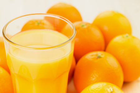 Glass of freshly pressed orange juice with oranges on wooden background. Healthy lifestyle concept.の写真素材