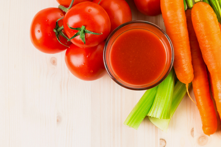 Glass of different vegetable juices with carrots, tomatoes and celery on wooden table. Healthy eating, drinks, diet and detox concept. Copy space for text. View from above. Flat lay.の写真素材