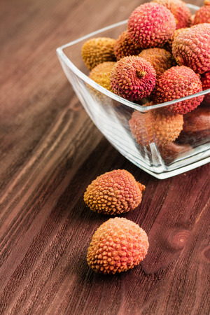Fresh organic lychee fruit on brown wooden background in glass bowl. Tropical fruit. View from above. Copy space for text.の写真素材