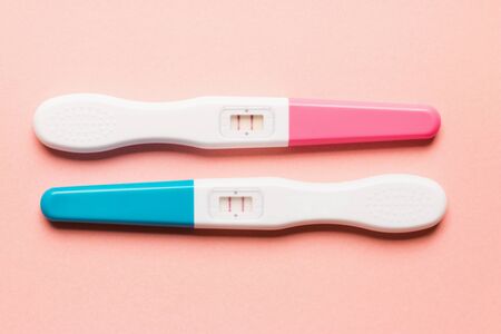 Positive pink and blue plastic pregnancy tests on pink background. Top view. Flat lay. Copy space for text.の写真素材