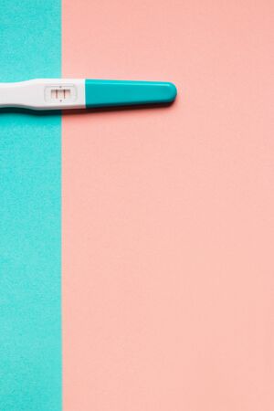 Positive blue plastic pregnancy test on pink and blue background. Top view. Flat lay. Copy space for text.の写真素材