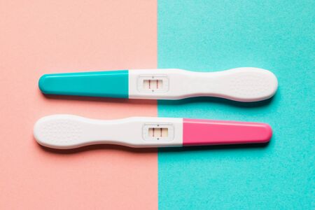 Positive pink and blue plastic pregnancy tests on pink and blue background. Top view. Flat lay. Copy space for text.の写真素材