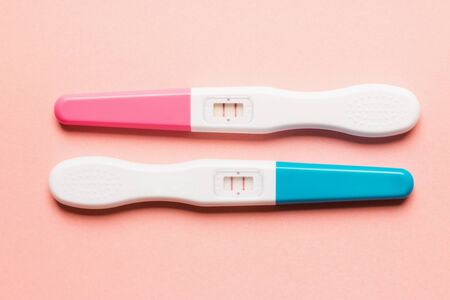 Positive pink and blue plastic pregnancy tests on pink background. Top view. Flat lay. Copy space for text.の写真素材