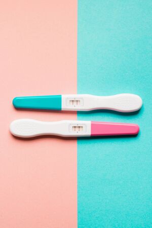 Positive pink and blue plastic pregnancy tests on pink and blue background. Top view. Flat lay. Copy space for text.の写真素材