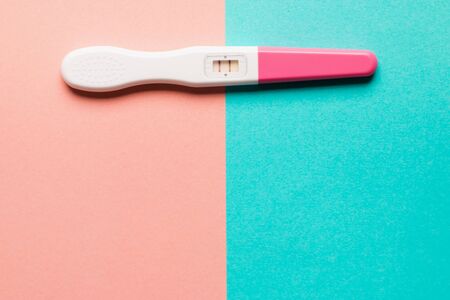 Positive pink plastic pregnancy test on pink and blue background. Top view. Flat lay. Copy space for text.の写真素材