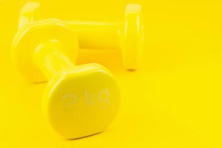 Sport background. Yellow dumbbells on yellow background. Still life and health care concept. View from above. Copy space for text.の写真素材