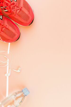 Sport background. White headphones, a bottle of fresh water and pink sneakers on pink background. Still life and health care concept. Flat lay, view from above. Copy space for text.の写真素材