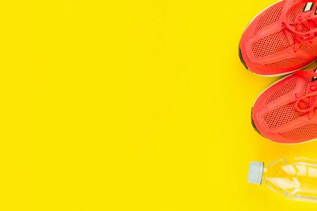 Sport background. Bottle of fresh water and pink sneakers on yellow background. Still life and health care concept. Flat lay, view from above. Copy space for text.の写真素材