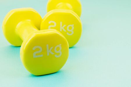 Sport background. Yellow dumbbells on blue background. Still life and health care concept. View from...