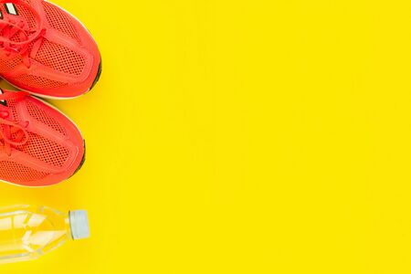Sport background. Bottle of fresh water and pink sneakers on yellow background. Still life and health care concept. Flat lay, view from above. Copy space for text.の写真素材