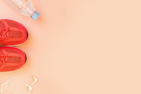 Sport background. White headphones, a bottle of fresh water and pink sneakers on pink background. Still life and health care concept. Flat lay, view from above. Copy space for text.の写真素材