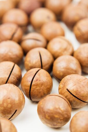 Raw not peeled whole macadamia nuts isolated on white. Healthy food. Protein source. View from above.の写真素材