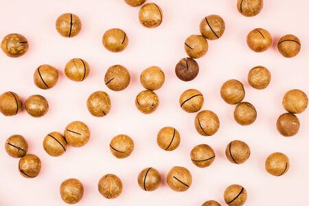 Raw not peeled whole macadamia nuts on pink background. Healthy food. Protein source. Flat lay. View from above.の写真素材