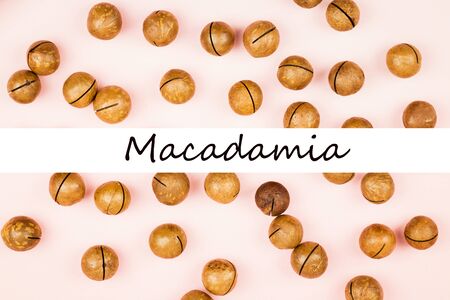 Raw not peeled whole macadamia nuts on pink background. Healthy food. Protein source. Flat lay. View from above with text Macadamia.の写真素材