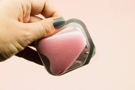 Close up of woman hand holding menstrual sponge tampon in package on pink background with copy space for text. Feminine hygiene product,の写真素材