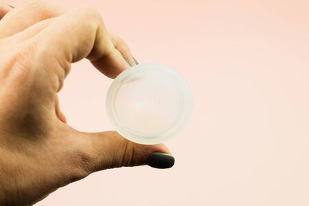 Close up of woman hand holding menstrual cup on pink background with copy space for text. Zero waste...