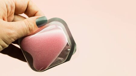 Close up of woman hand holding menstrual sponge tampon in package on pink background with copy space for text. Feminine hygiene product,の写真素材