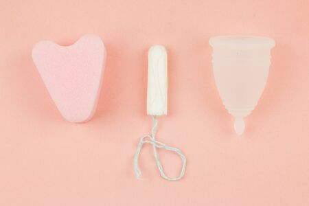Close up of menstrual cup, tampon and sponge on pink background with copy space for text. Feminine hygiene products, Top view.の写真素材