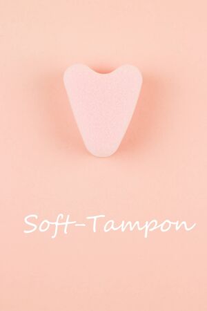Close up of menstrual sponge tampon on pink background with text soft-tampon. Feminine hygiene product, View from above.の写真素材