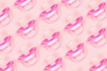 Pattern pink baby pacifiers, dummy with rubber nipple on pink background. Flat lay. Top view.の写真素材