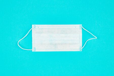 A close up of medical mask on blue background. Coronavirus protection. Copy paste for text. Top view. Flat lay.の写真素材