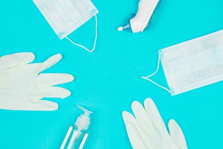 Medical mask, thermometer, white latex gloves and hand sanitizer gel on blue background. Coronavirus protection. Top view. Flat lay.の写真素材