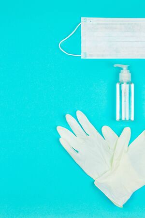 Medical mask, white latex gloves and hand sanitizer gel on blue background. Coronavirus protection. Top view. Flat lay.の写真素材